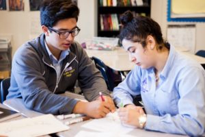 Teacher and student working together on an assignment at a table