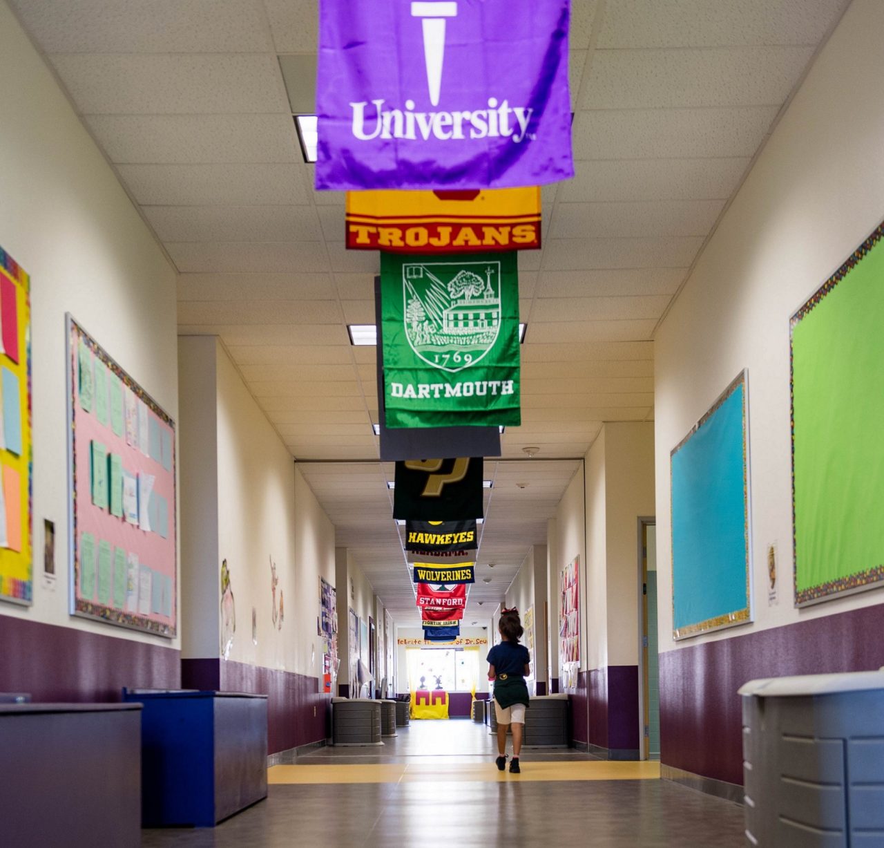 Aspire student walking down the hallway with flags hanging from the ceiling